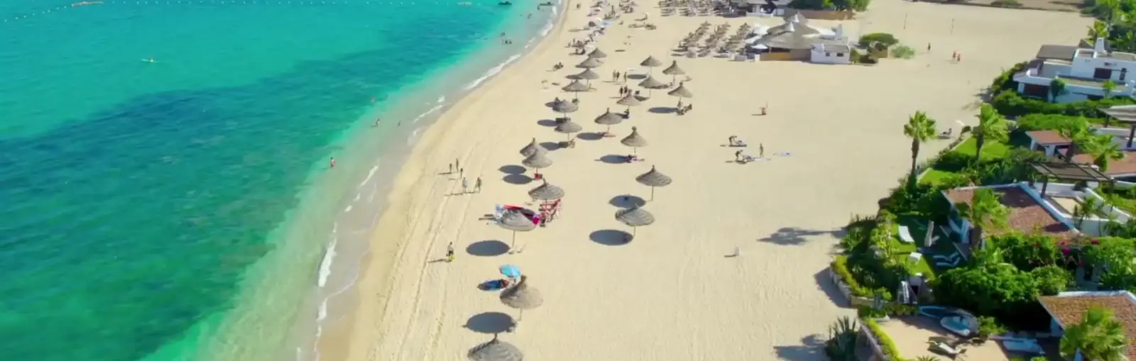 Dronebeeld van het lange zandstrand van Martil met parasols en turquoise zee